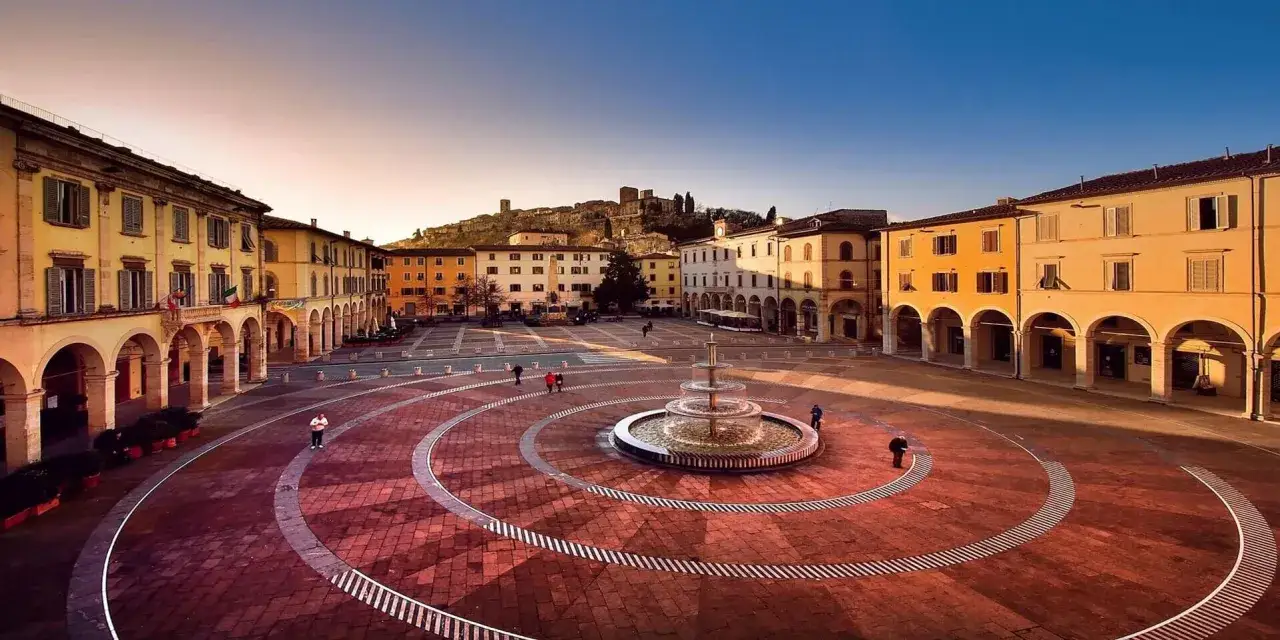 Piazza del Duomo a Colle Val d'Elsa, con la fontana centrale e il borgo medievale sullo sfondo.