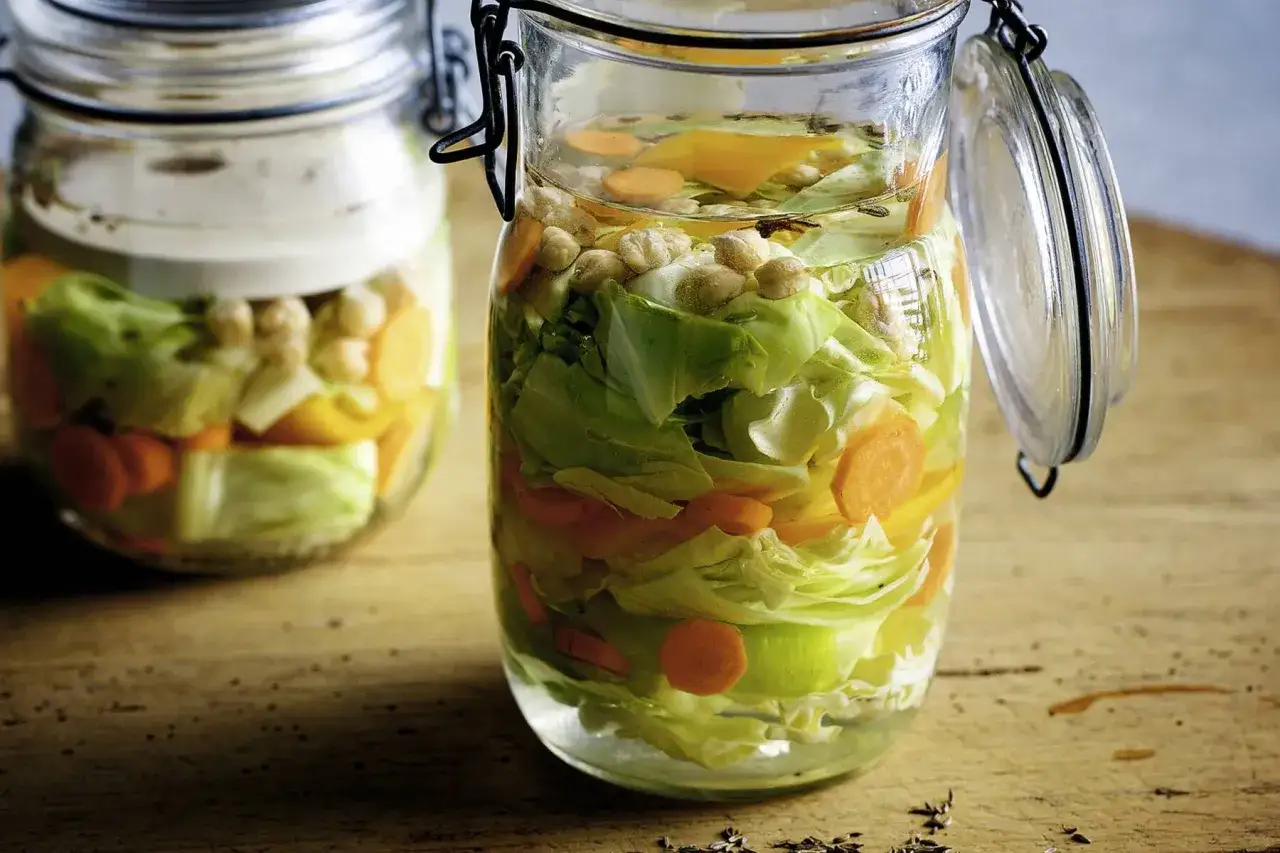 Zwei Gläser mit spitzkohl fermentieren: Kohl, Karotten und Kichererbsen in Salzlake.