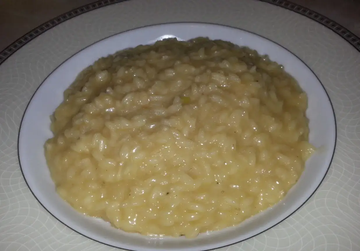 Kremowe risotto szafranowe, pachnące i złociste, podane na białym talerzu. Idealne na elegancki obiad.