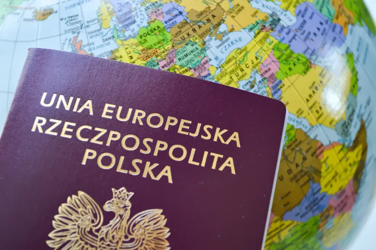 Polski paszport na tle globusa. Planujesz podróż i zastanawiasz się nad koszt paszportu?