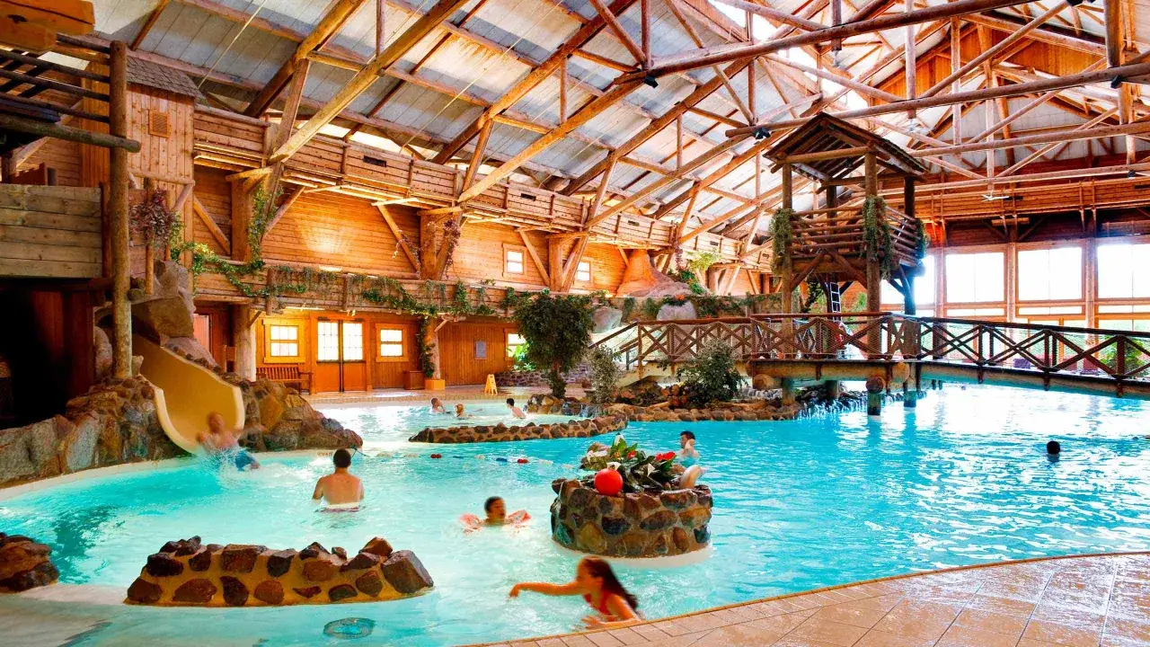 Diversión acuática en el Davy Crockett Ranch, con tobogán, piscina y un puente rústico bajo un techo de madera.