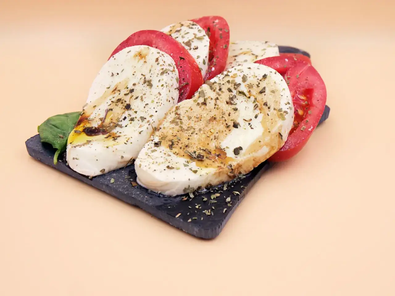 Plastry pomidora i mozzarelli, skropione oliwą i ziołami. Czy ser mozzarella jest tłusty? Ten wygląda apetycznie!