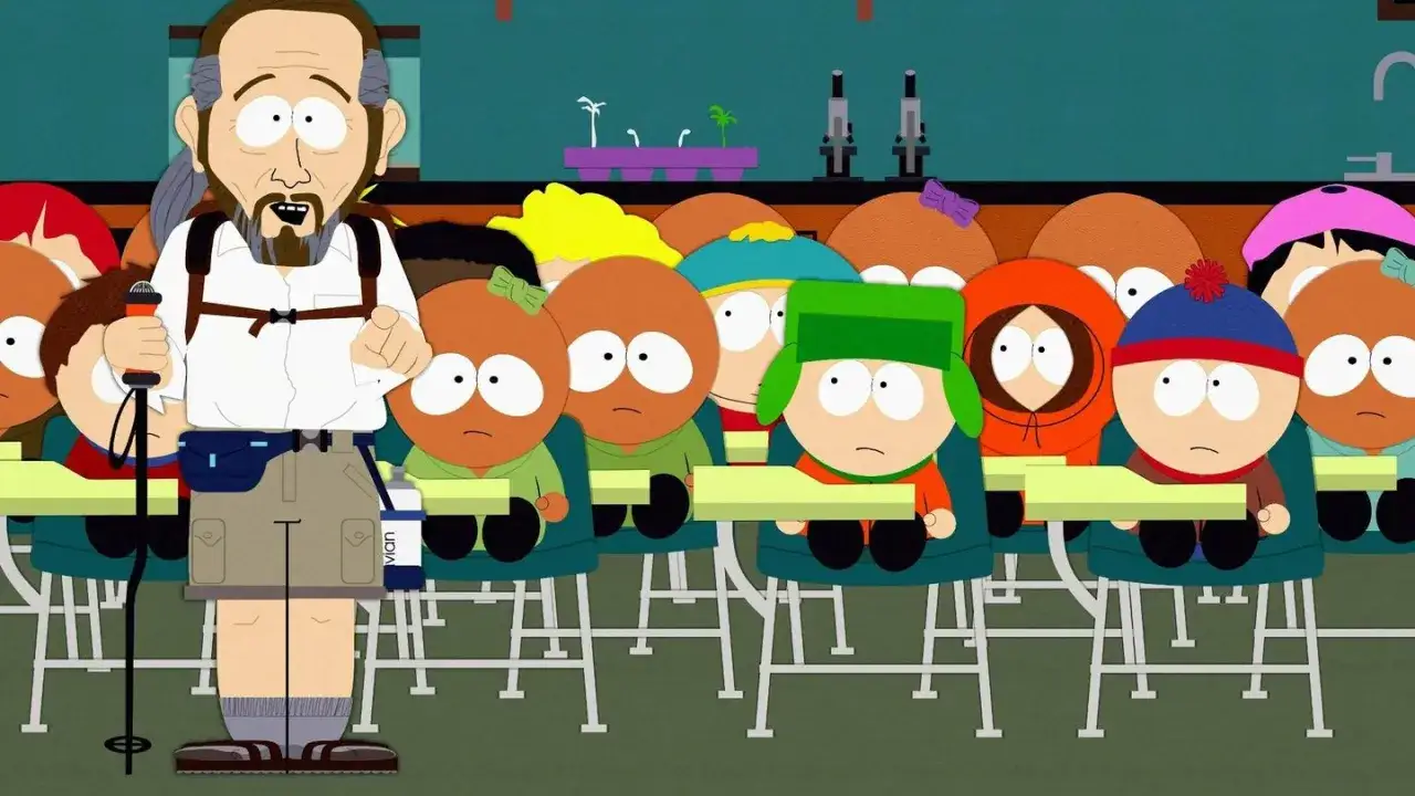 Nauczyciel z plecakiem i laską prowadzi lekcję dla dzieci z South Park. W tle widać mikroskopy i rośliny.