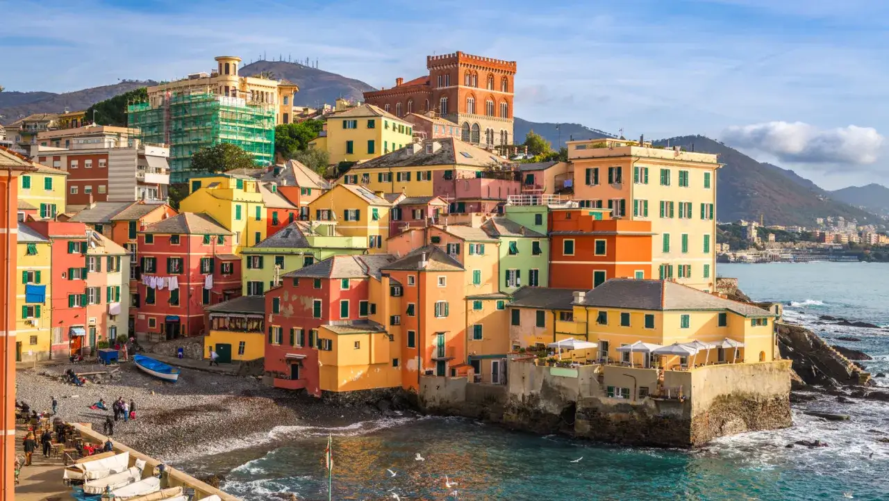 F&auml;rgstarka hus kl&auml;ttrar uppf&ouml;r kullen i Camogli, Italien, med havet som sk&ouml;ljer mot klipporna nedanf&ouml;r.