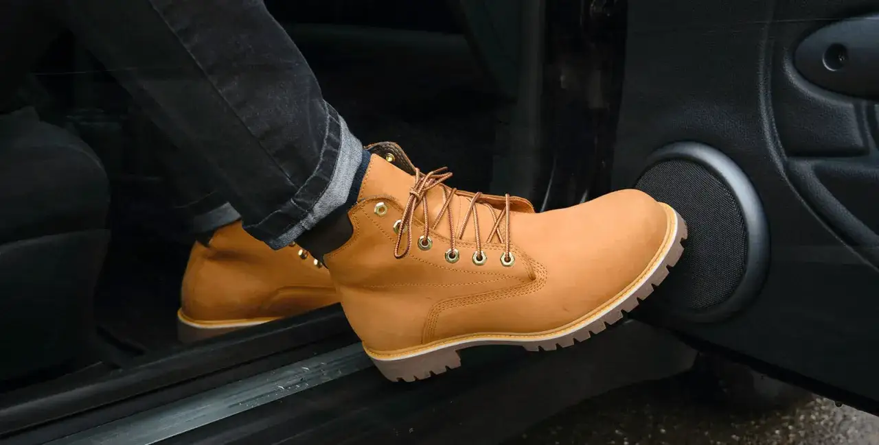 Botas de cuero color caramelo, un estilo clásico entre los tipos de botas, con cordones y suela gruesa, apoyadas en el interior de un coche.