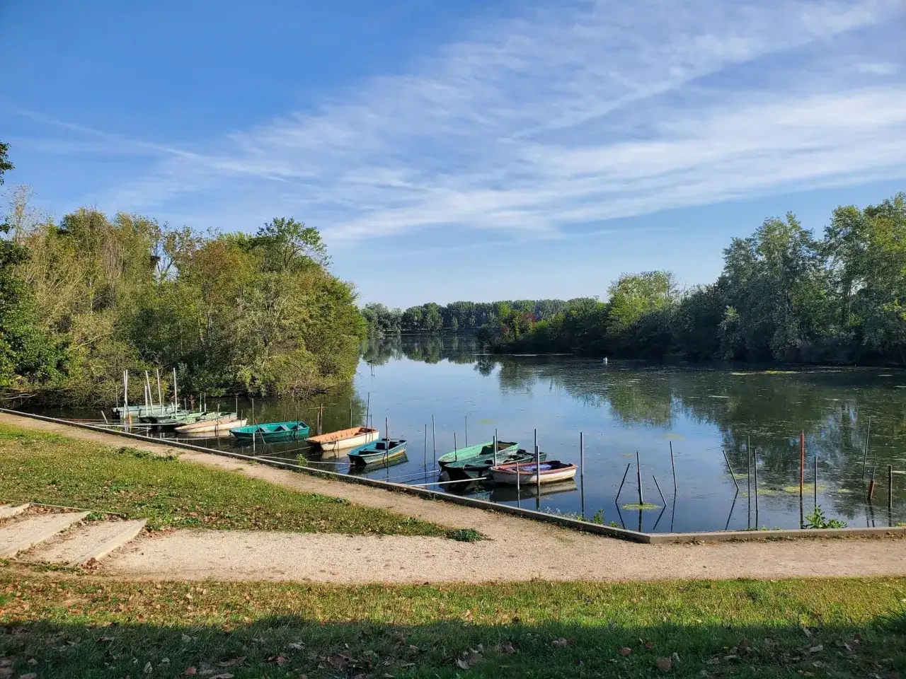 Plusieurs bateaux color&eacute;s sont amarr&eacute;s sur le lac de Viry-Ch&acirc;tillon, sous un ciel bleu parsem&eacute; de nuages l&eacute;gers.