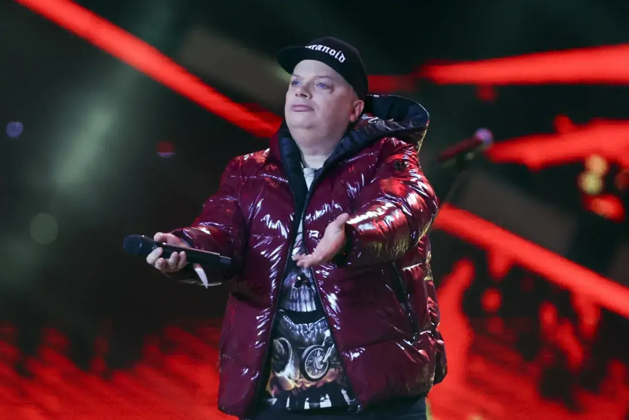 Krzysztof Skiba w błyszczącej kurtce i czapce z napisem 