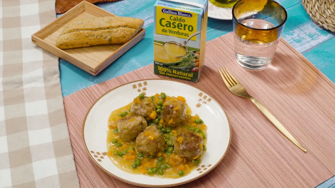 Albondigas a la jardinera con guisantes y zanahoria en salsa, acompa&ntilde;adas de pan y caldo de verduras.