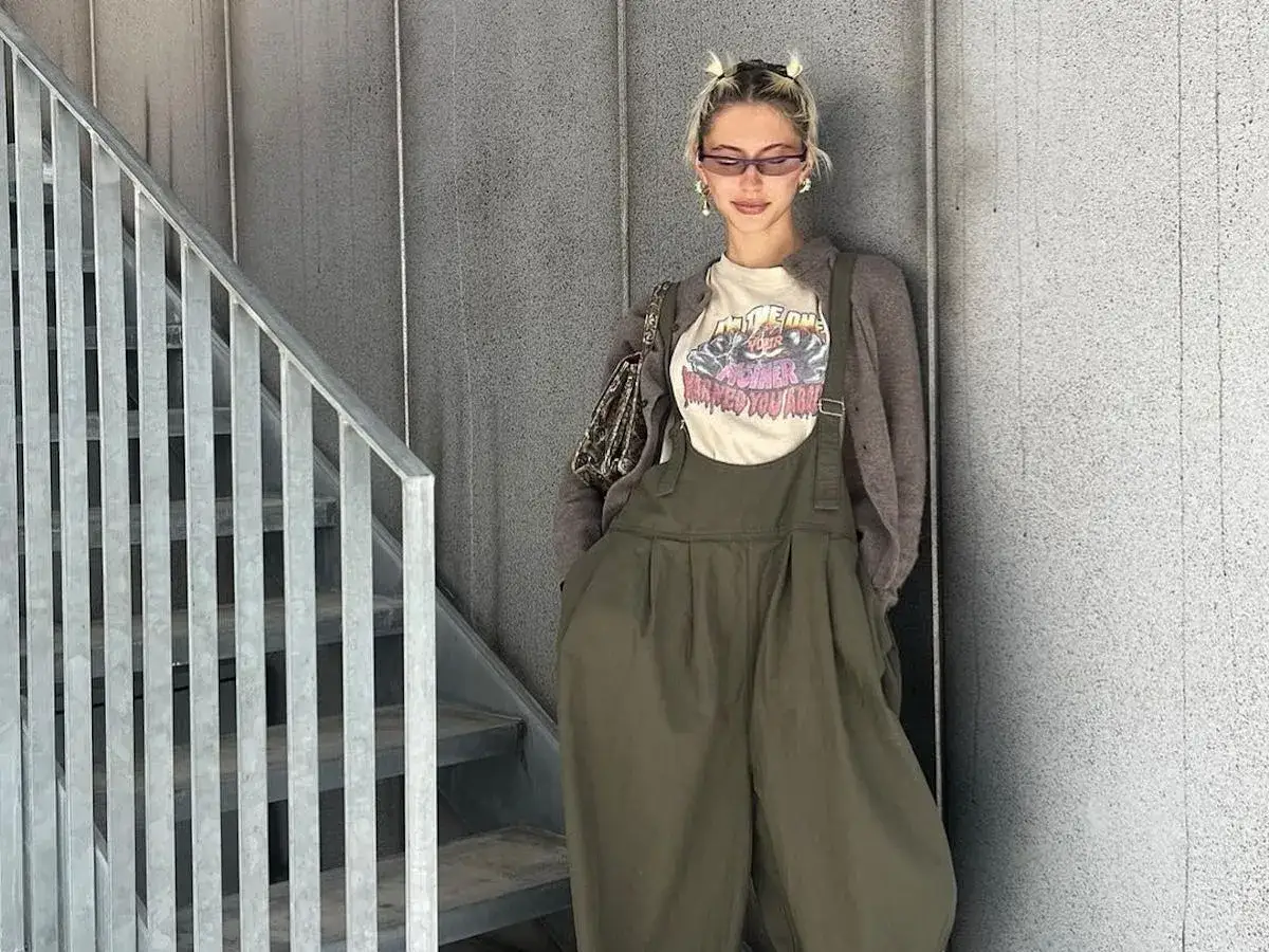Iris Law, con su estilo &uacute;nico, posa con un overol verde y camiseta gr&aacute;fica.