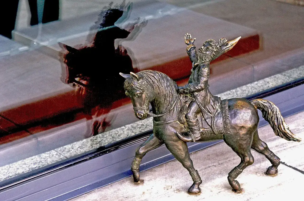 Figurka krasnala na koniu, jedna z wielu atrakcji dla dzieci we Wrocławiu, odbija się w szybie.