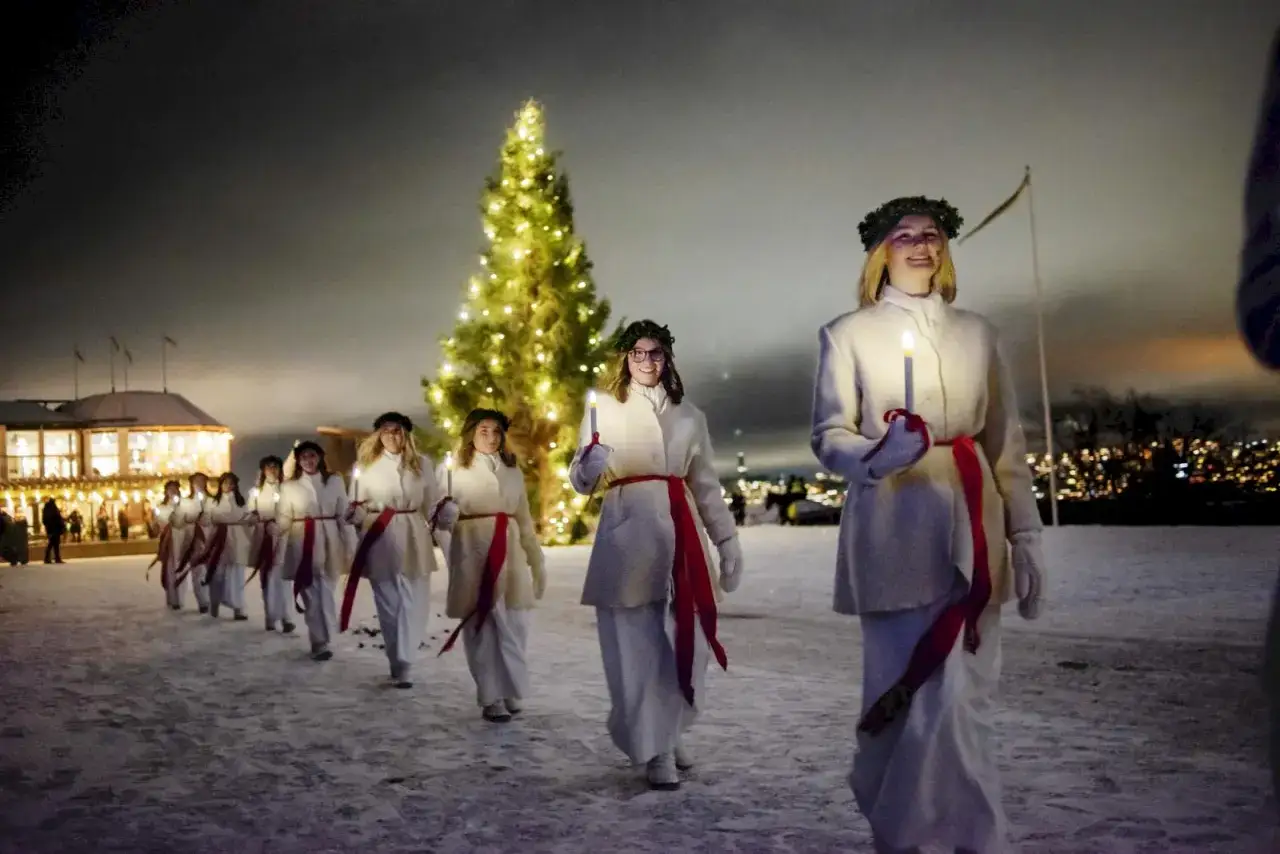 Lucia-t&aring;g i sn&ouml;ig julnatt i Stockholm, med en glittrande julgran och ljus.