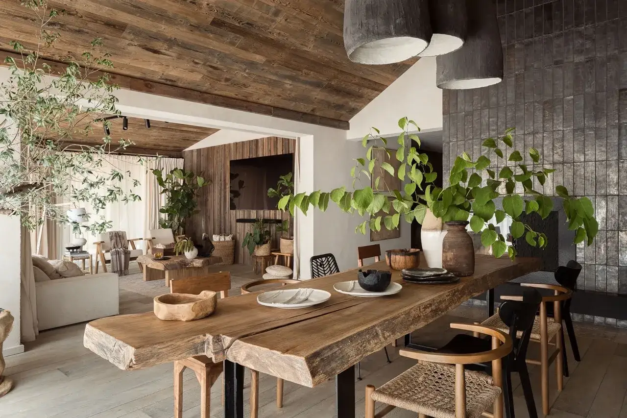 Un salon et une salle à manger baignés de lumière, avec un design biophilique. Bois brut, plantes luxuriantes et textures naturelles créent une atmosphère apaisante.