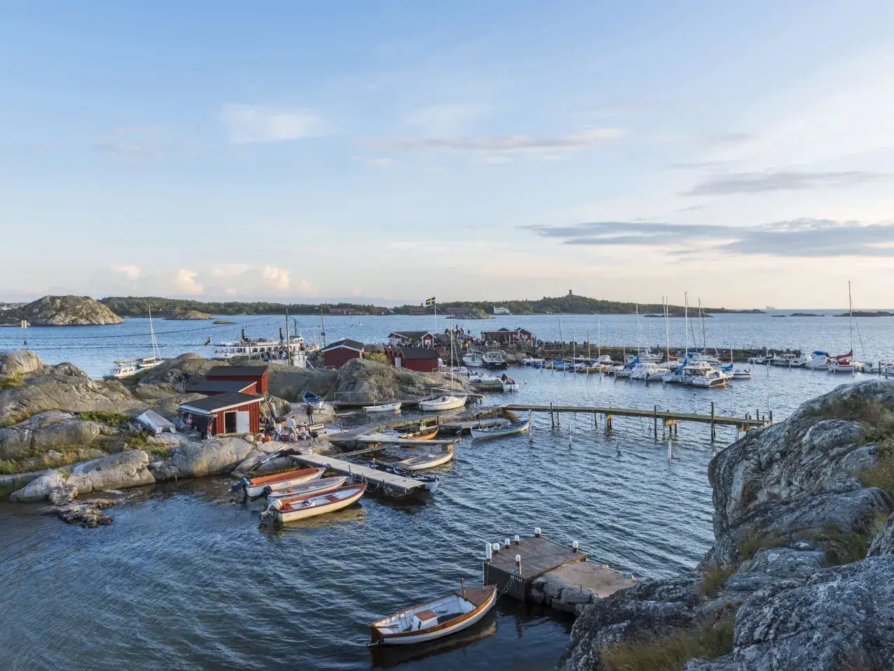 En idyllisk hamn med röda sjöbodar och båtar, en av de charmiga platserna att besöka i Göteborgs skärgård.