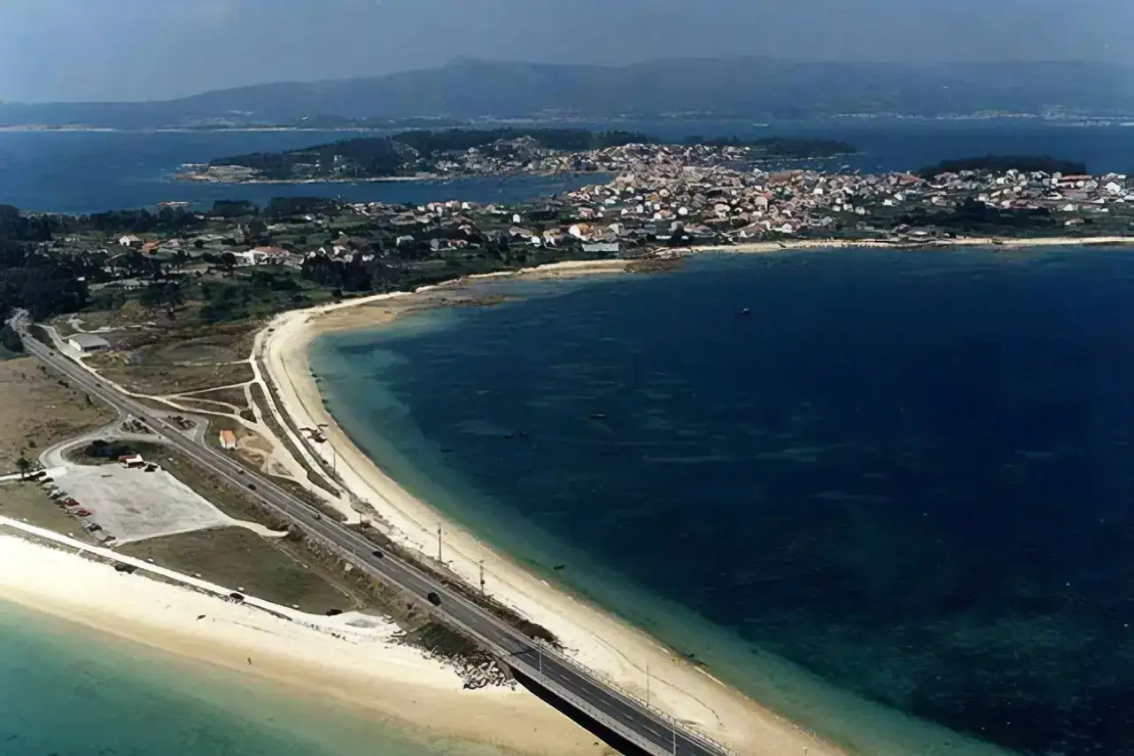 Vista aérea de la Illa de Arousa, con sus casas blancas, playas doradas y el mar azul intenso.