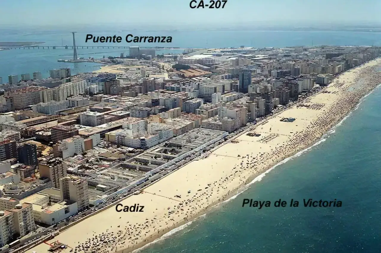 Blick auf die belebte Playa de la Victoria in Cadiz, mit der Puente Carranza im Hintergrund.