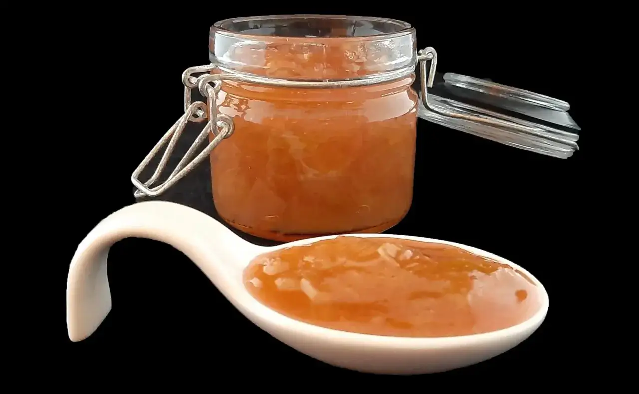 Un pot de confiture de rhubarbe maison, avec une cuill&egrave;re en porcelaine remplie de cette d&eacute;licieuse confiture de rhubarbe.