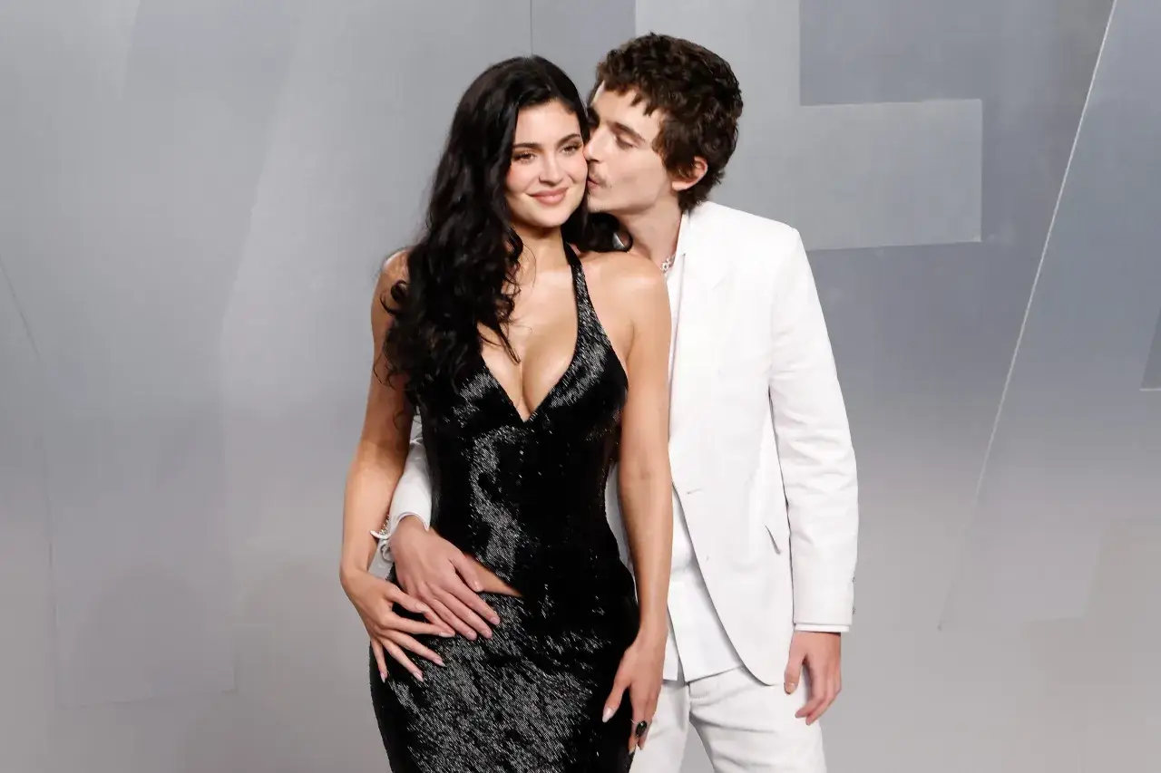 Timothée Chalamet küsst Kylie Jenner auf die Wange, während sie in einem glitzernden schwarzen Kleid posiert.