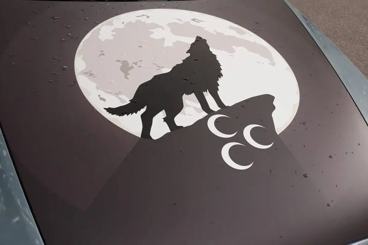 Ein grauer Wolf heult den Mond an, der auf einem Felsen steht. Drei wei&szlig;e Halbmonde sind unter ihm.