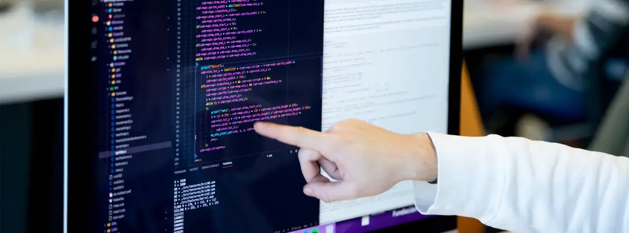 Dedo señalando código en pantalla. Aprender a programar es clave para saber qué estudiar para teletrabajar en desarrollo.