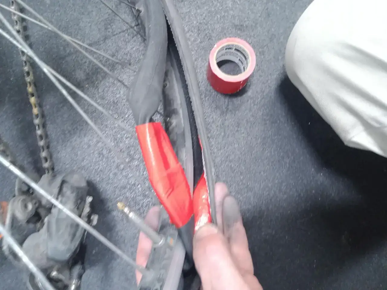 Naprawa przebitej dętki w rowerze. Czerwona taśma izolacyjna pomaga w tym procesie.