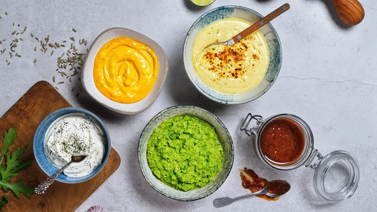 Olika s&aring;ser och r&ouml;ror, inklusive en gr&ouml;n &auml;rtpur&eacute; och en vit med dill, perfekt f&ouml;r att testa ett nytt dillolja recept.