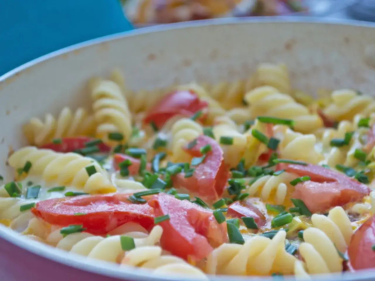 Nudeln mit Ei, Tomaten und Schnittlauch in einer Pfanne. Ein leckeres und einfaches Gericht.