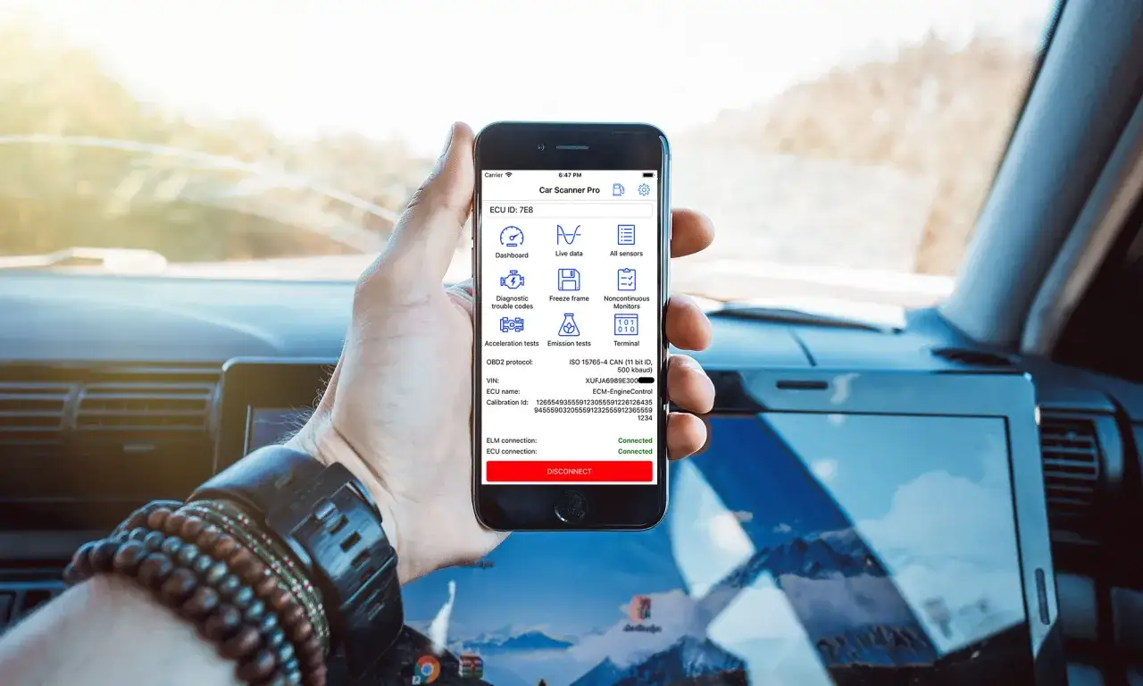 Ręka trzyma smartfon z aplikacją Car Scanner Pro, która wykorzystuje oprogramowanie ELM 327 do diagnostyki samochodu.