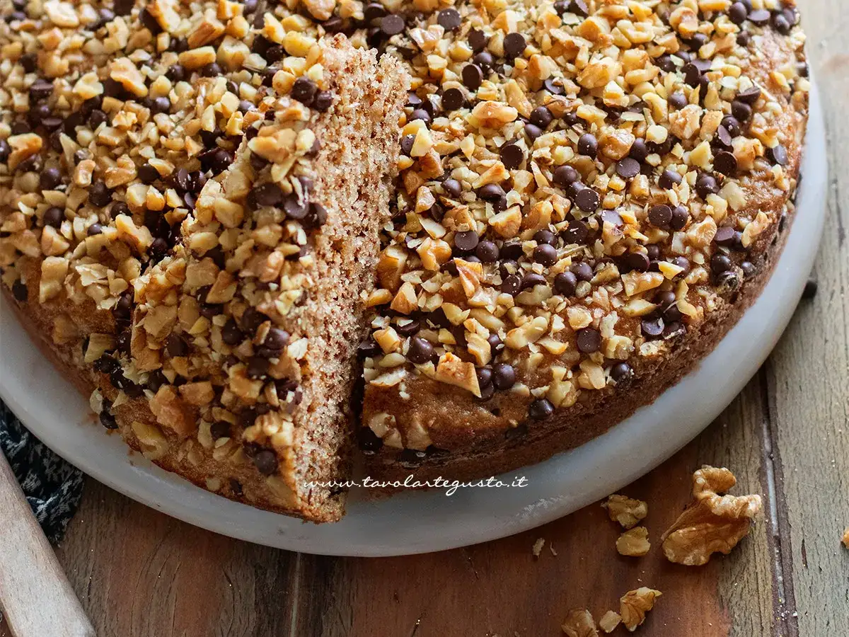 Una deliziosa torta di noci e gocce di cioccolato, con una fetta tagliata per mostrare la sua morbidezza.