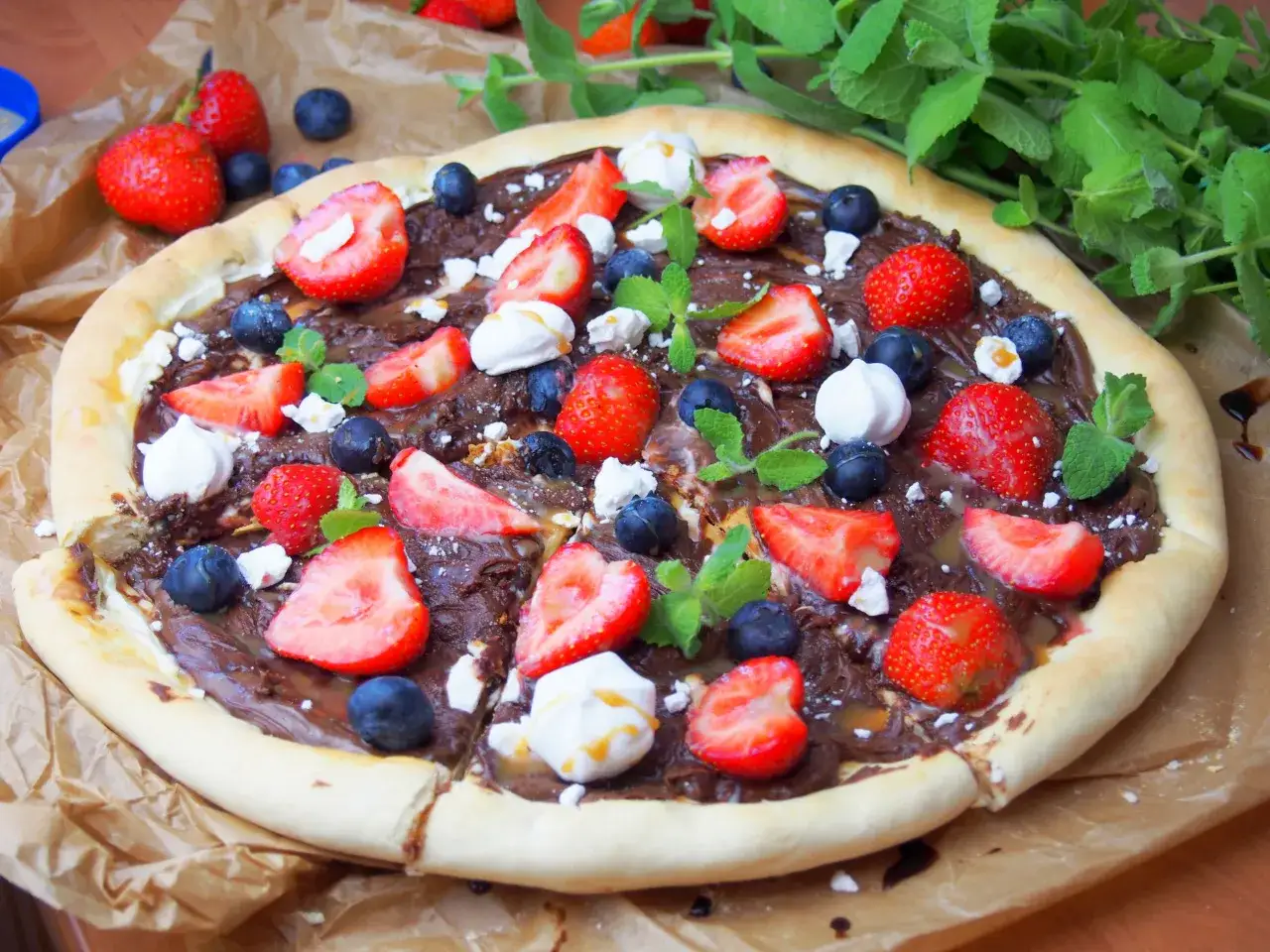 Pyszna pizza na słodko z kremem czekoladowym, truskawkami, borówkami i piankami.