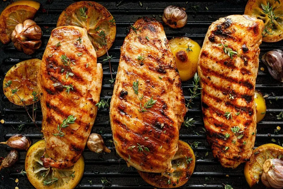 Soczyste piersi z kurczaka po grillowaniu, z przypieczonymi plastrami cytryny i czosnkiem. Idealna marynata do piersi z kurczaka na grilla.