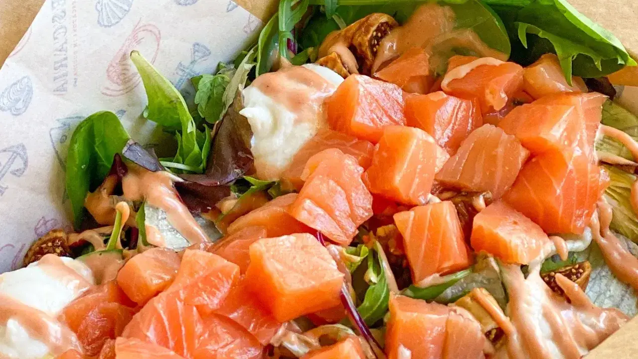 Un'insalata di mare fresca e colorata, con cubetti di salmone succulento, verdure croccanti e una salsa rosata.