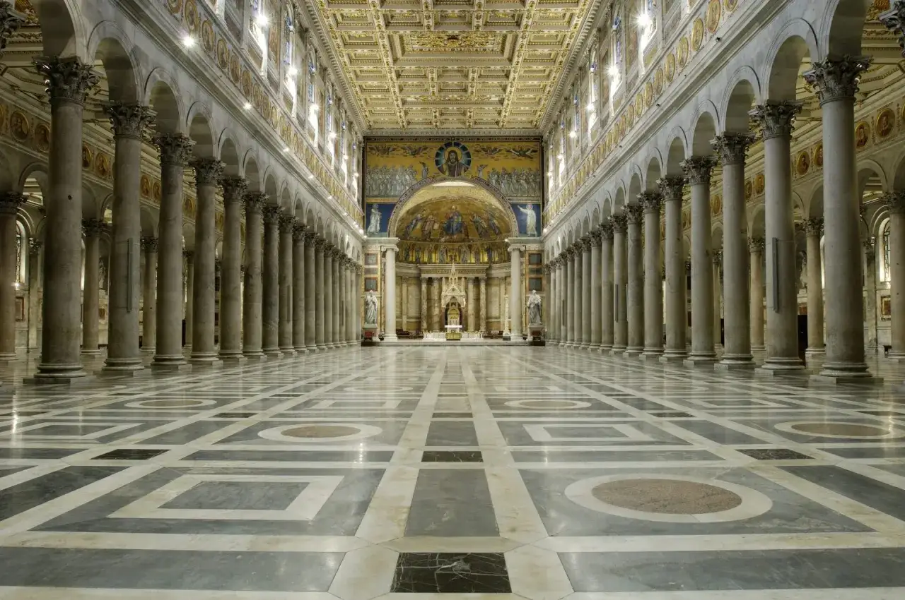Interno di San Paolo fuori le Mura: navata maestosa con colonne corinzie, soffitto dorato e mosaici absidali.