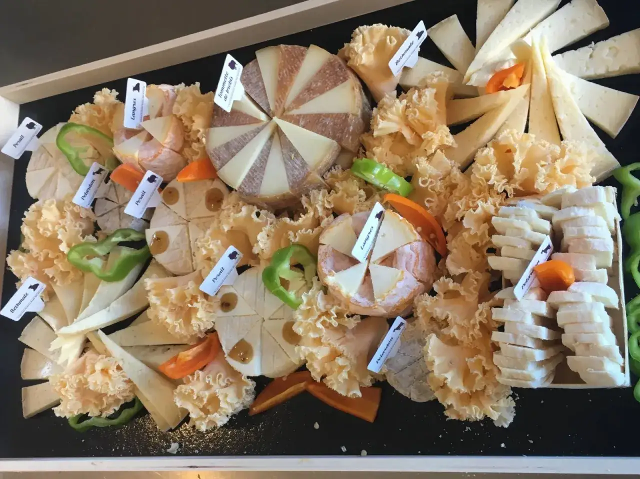 Plateau de fromages vari&eacute;s, dont un fromage de Bourgogne, d&eacute;cor&eacute; de poivrons et de fruits secs.