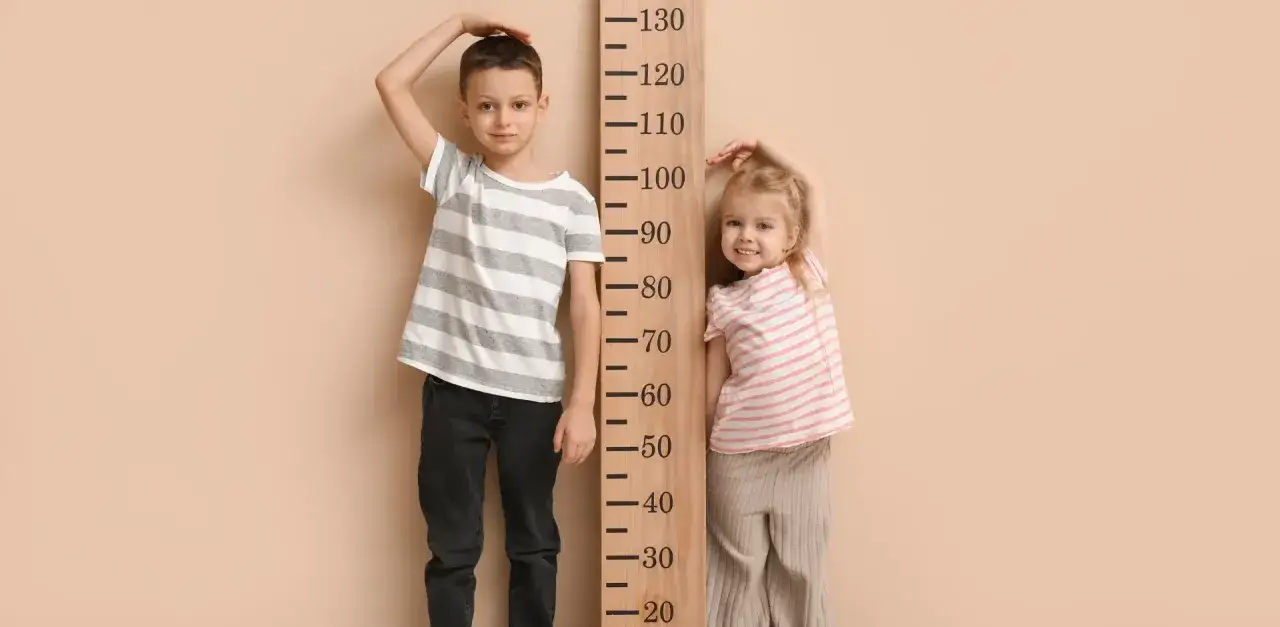 Chłopiec mierzy ok. 128 cm, co może odpowiadać wiekowi 7-8 lat. Obok stoi młodsza dziewczynka.