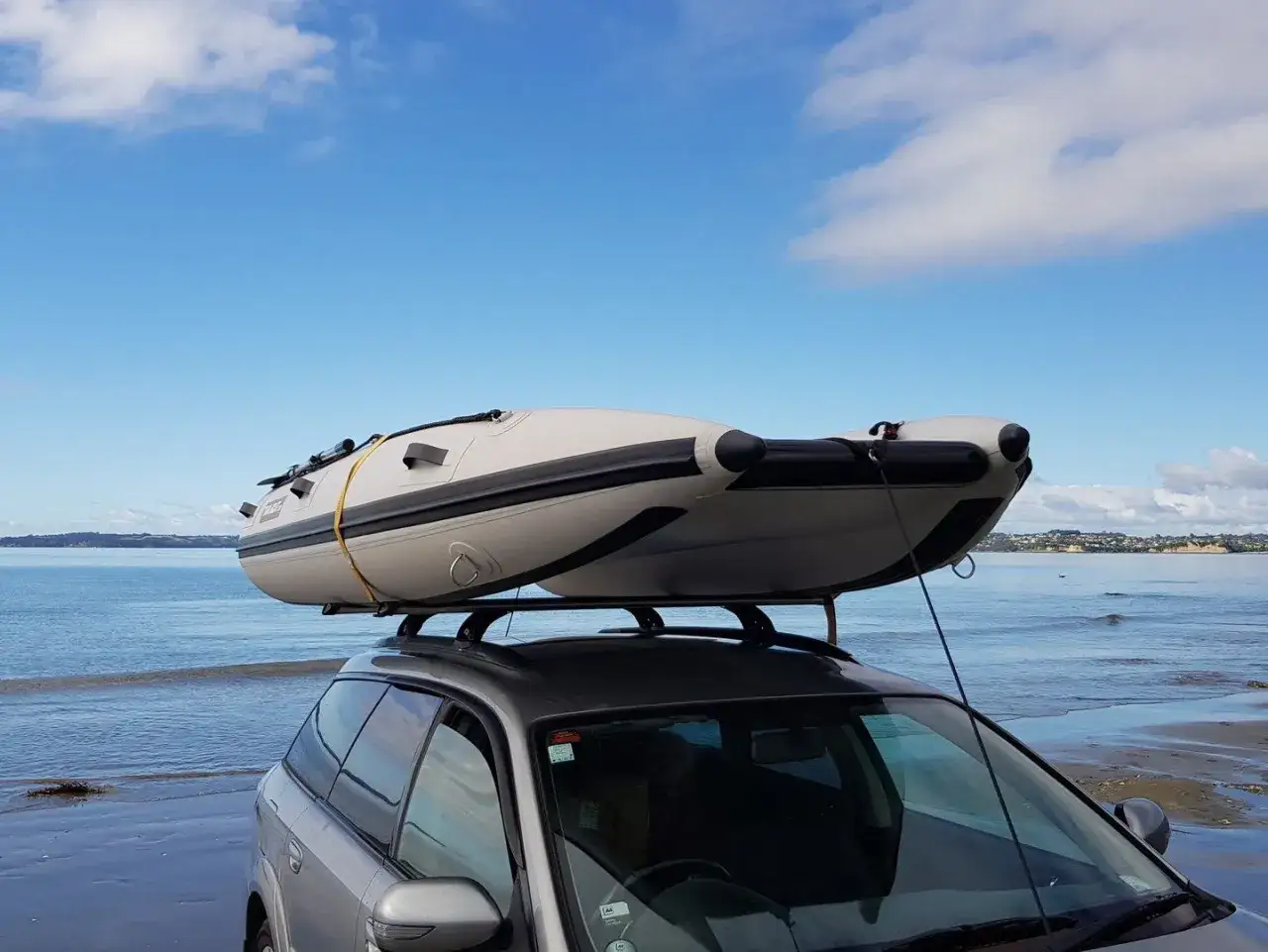 Ein Schlauchboot wird auf dem Autodach transportiert, bereit f&uuml;r den Wasserspa&szlig; am Strand.