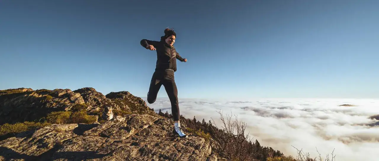Une coureuse saute au-dessus des nuages, un paysage de trail actualité à couper le souffle.