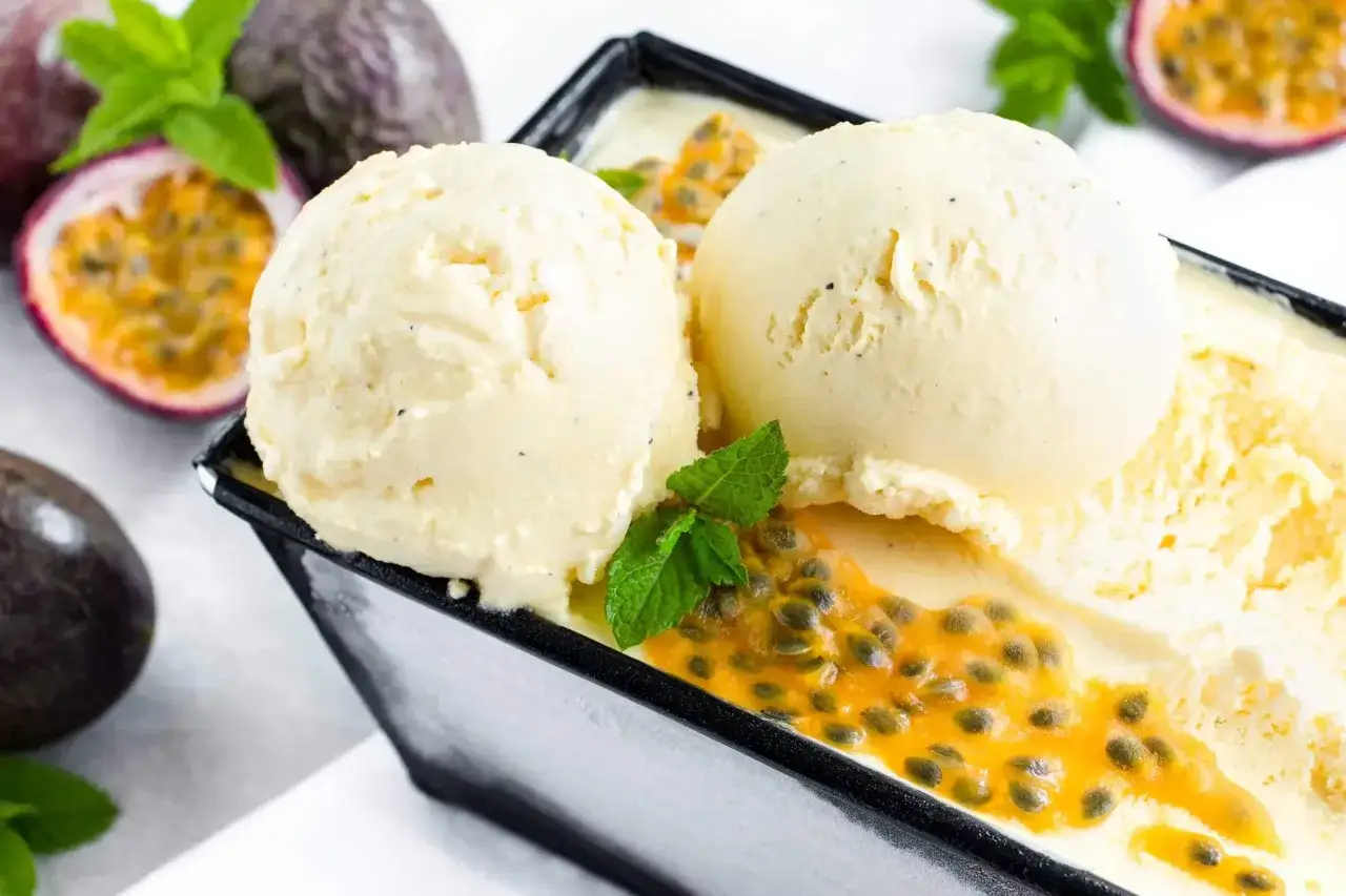 Zwei Kugeln cremiges Maracuja Eis mit frischer Minze und Passionsfruchtkernen. Ein tropischer Genuss!