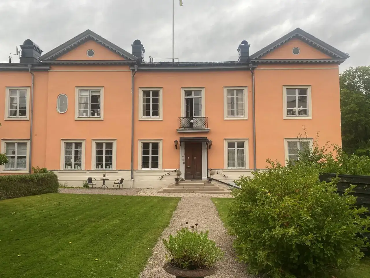 Ett persikof&auml;rgat hus med m&aring;nga f&ouml;nster och en vacker tr&auml;dg&aring;rd. Kanske en plats f&ouml;r gemensamma medlemsinsatser brf.