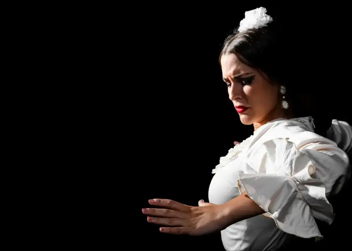 Una cantaora flamenca, con su mirada intensa y su vestido blanco de volantes, transmite la pasi&oacute;n del flamenco.
