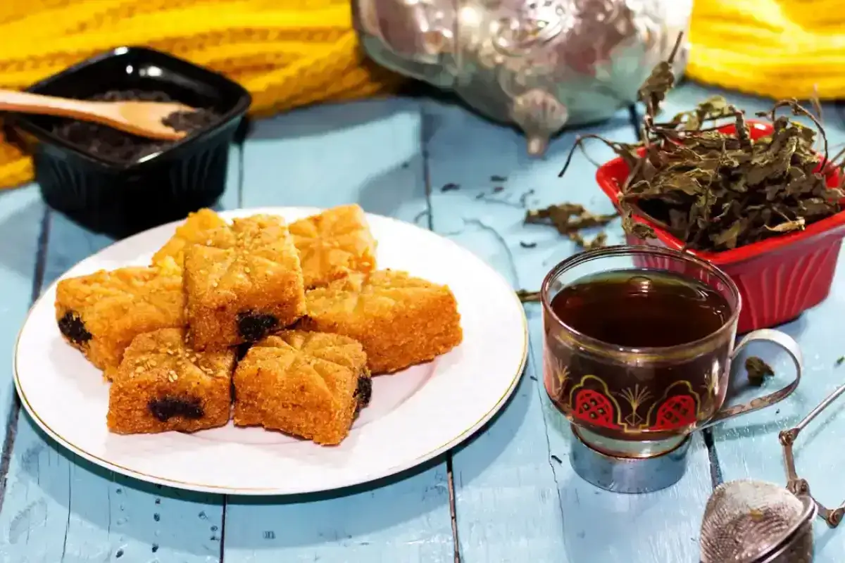 D&eacute;licieux makrouts alg&eacute;riens sur une assiette, accompagn&eacute;s d'une tasse de th&eacute; et de feuilles de menthe. Une recette makrout alg&eacute;rien facile &agrave; partager.