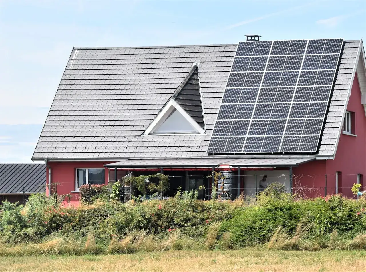 Dom z panelami fotowoltaicznymi na dachu, czerpiący czystą energię słoneczną.