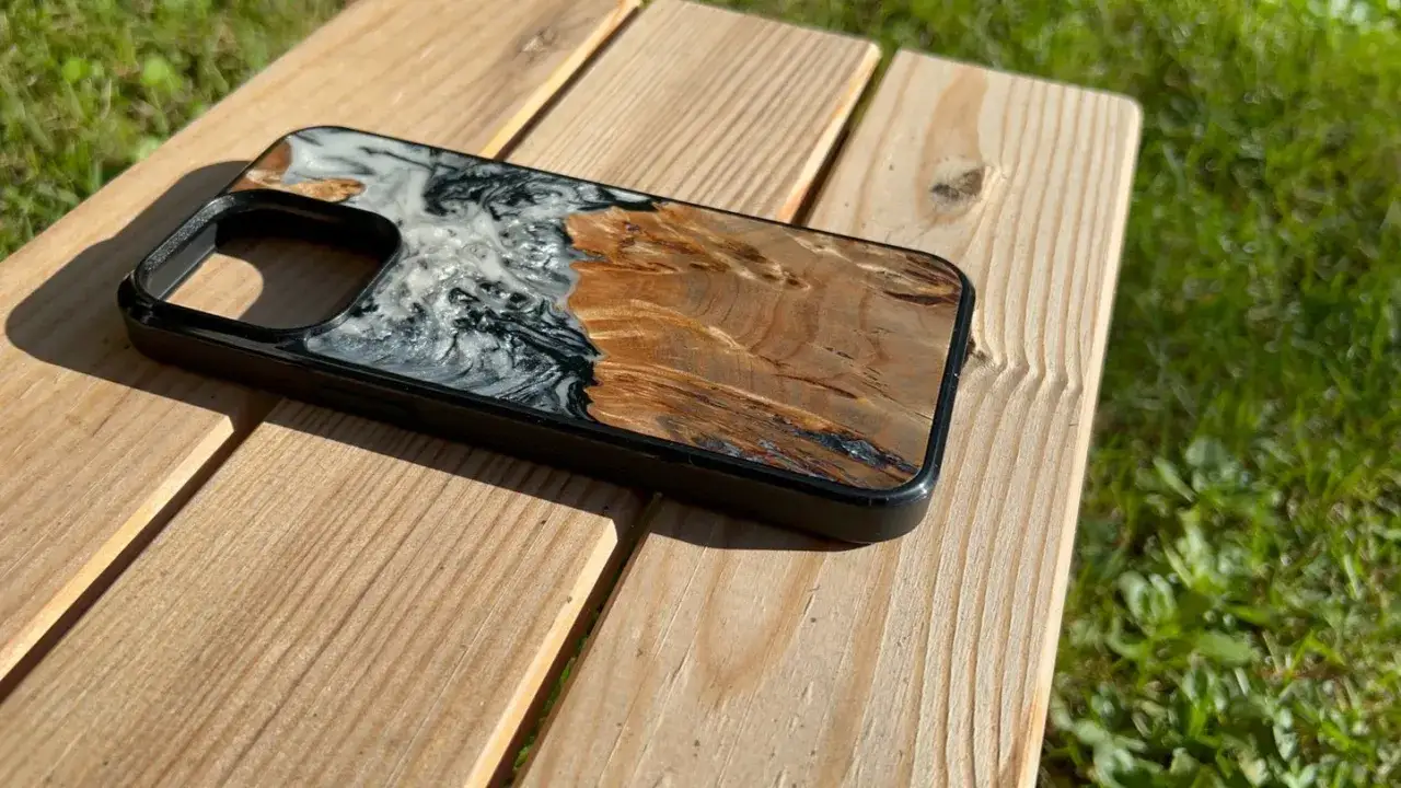 Coque de téléphone unique alliant la beauté du bois et la brillance de la résine époxy. Le contreplaqué offre une texture naturelle contrastant avec les marbrures de la résine.