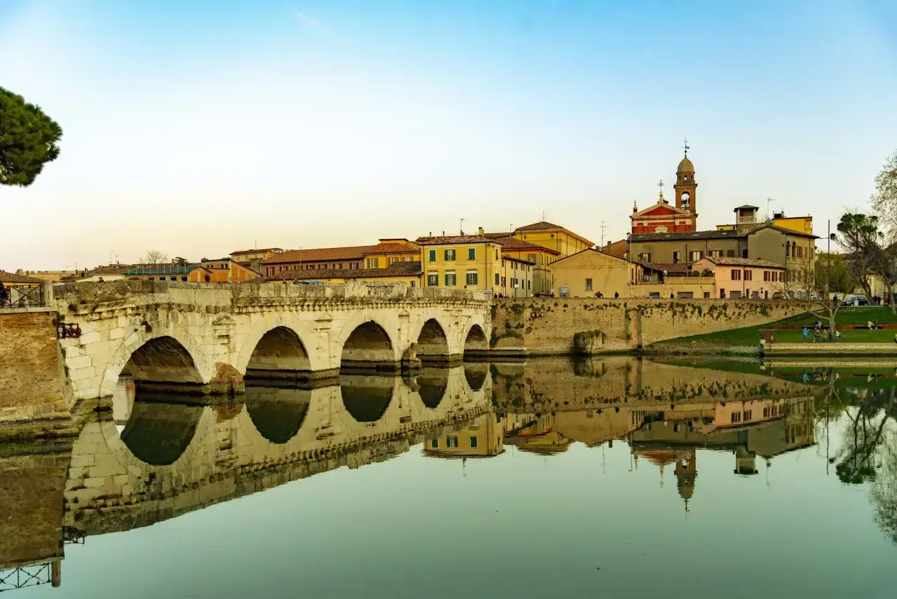 Ponte di Tiberio e il borgo antico, un classico tra le cose da vedere a Rimini, con riflessi sull'acqua calma.