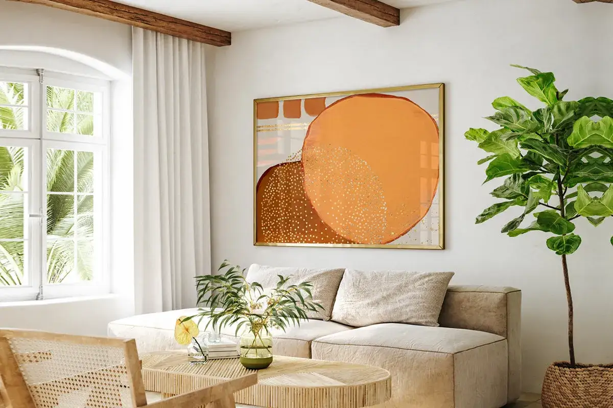 Un cuadro abstracto con c&iacute;rculos naranjas y marrones, salpicado de puntos dorados, evoca una **textura acuarela** en un sal&oacute;n moderno.