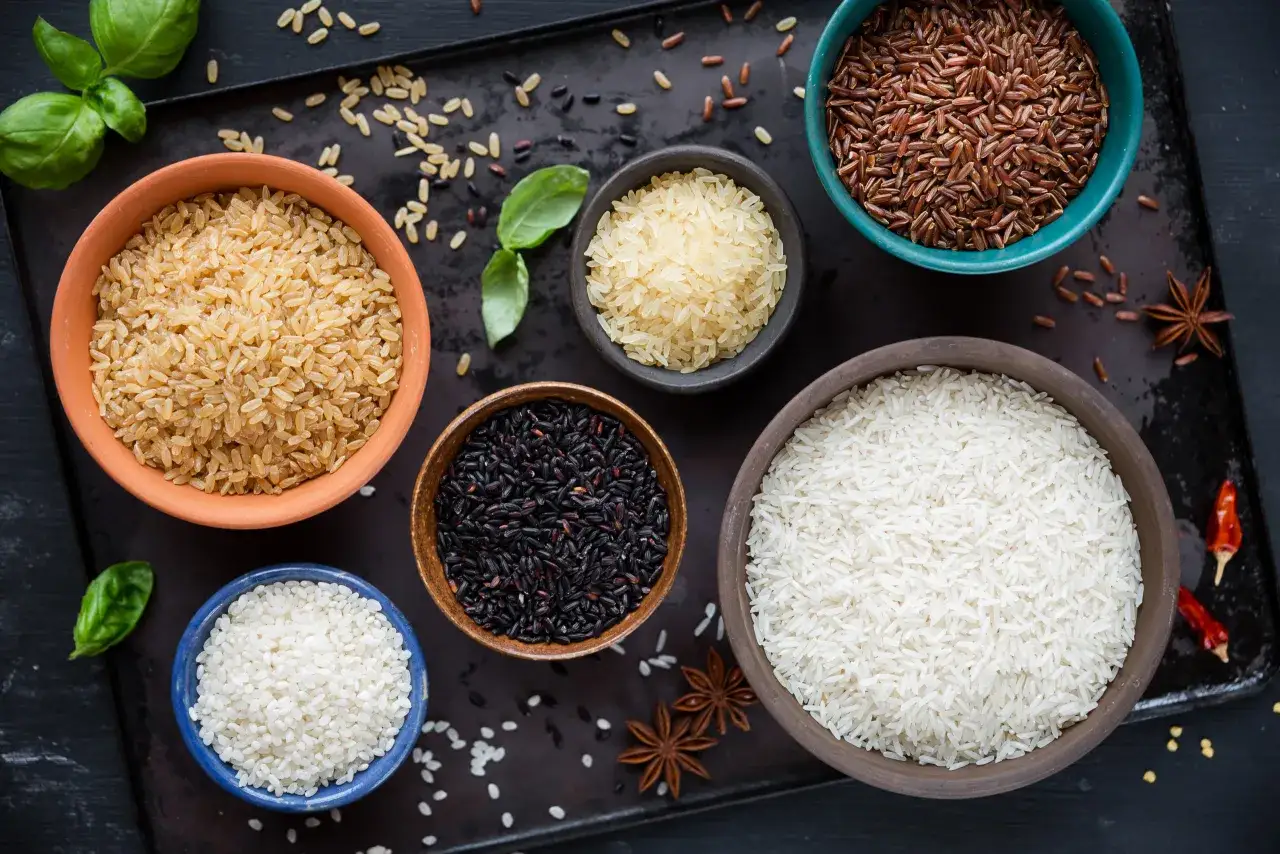 Verschiedene Reissorten in Schalen nebeneinander: Basmati, Langkorn, Vollkorn