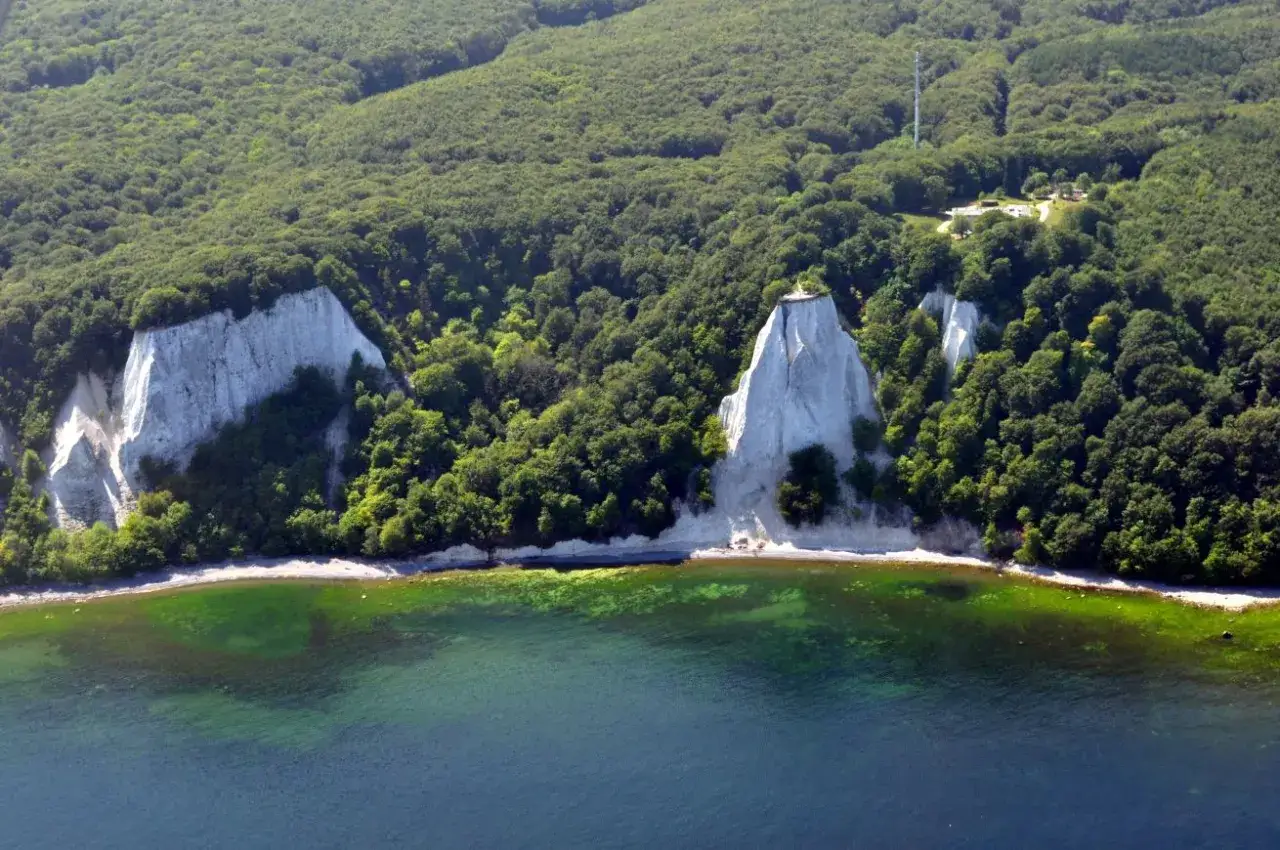 Weiße Kreidefelsen ragen aus dem grünen Wald auf der **Halbinsel Jasmund** empor, umspült von klarem, türkisfarbenem Wasser.