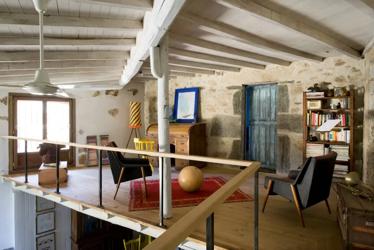 Espacio di&aacute;fano con vigas de madera y piedra, ideal para levantar tejado y hacer buhardilla. Muebles vintage y decoraci&oacute;n ecl&eacute;ctica.