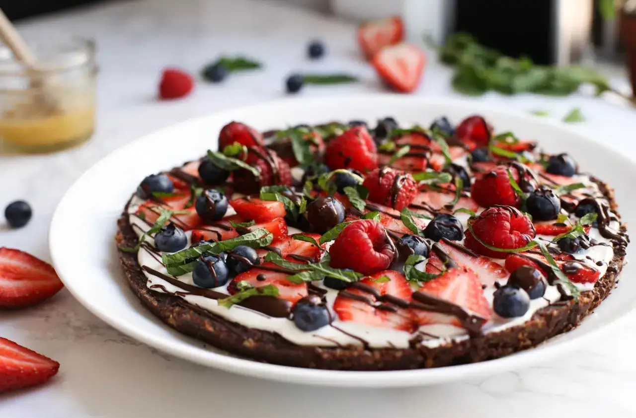 Pyszna pizza na słodko z kremem, truskawkami, malinami i borówkami, polana czekoladą.