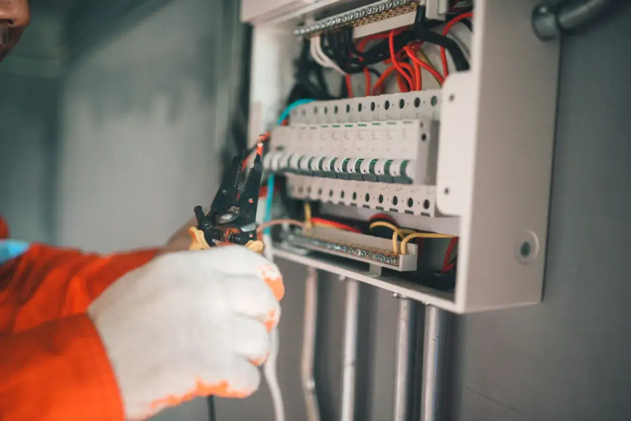 Elektryk w białych rękawicach pracuje przy skrzynce z bezpiecznikami. Czy wszystkie bezpieczniki muszą być do góry?