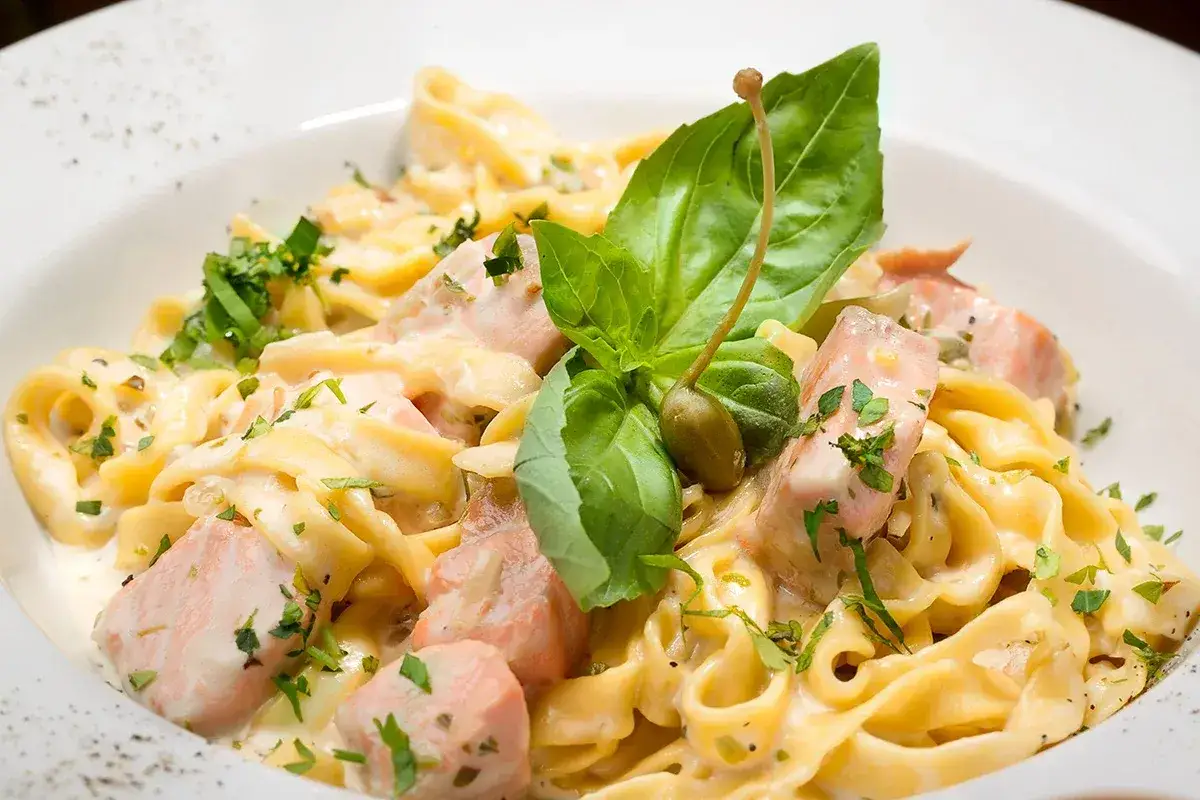 Cremige Tagliatelle al Salmone mit frischem Basilikum und Kapern. Ein Genuss für Feinschmecker.